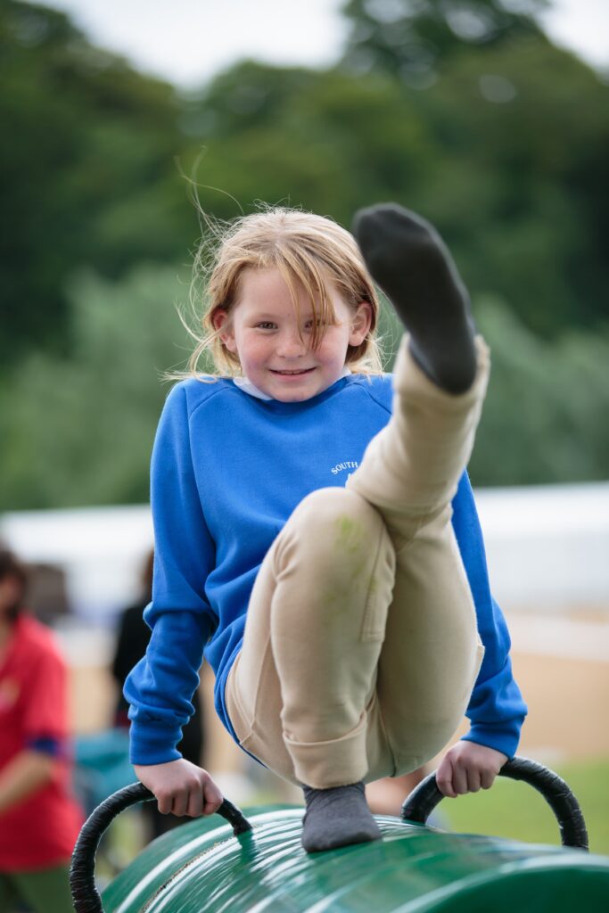 girl on vaulting barrel kicking leg up in seated position