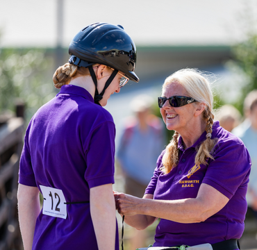 Participant with coach at our National Championships. The coach is helping to tie her rider number to her waist and offering encouragement.