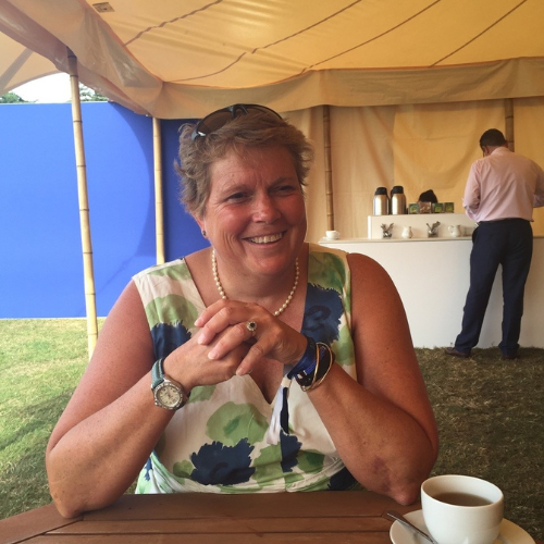 Rachel Vaughan-Johns sat in a marquee with a cup of coffee, in a green summer dress.