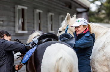 Natalie O'Rourke and volunteer saddle up piebald pony.