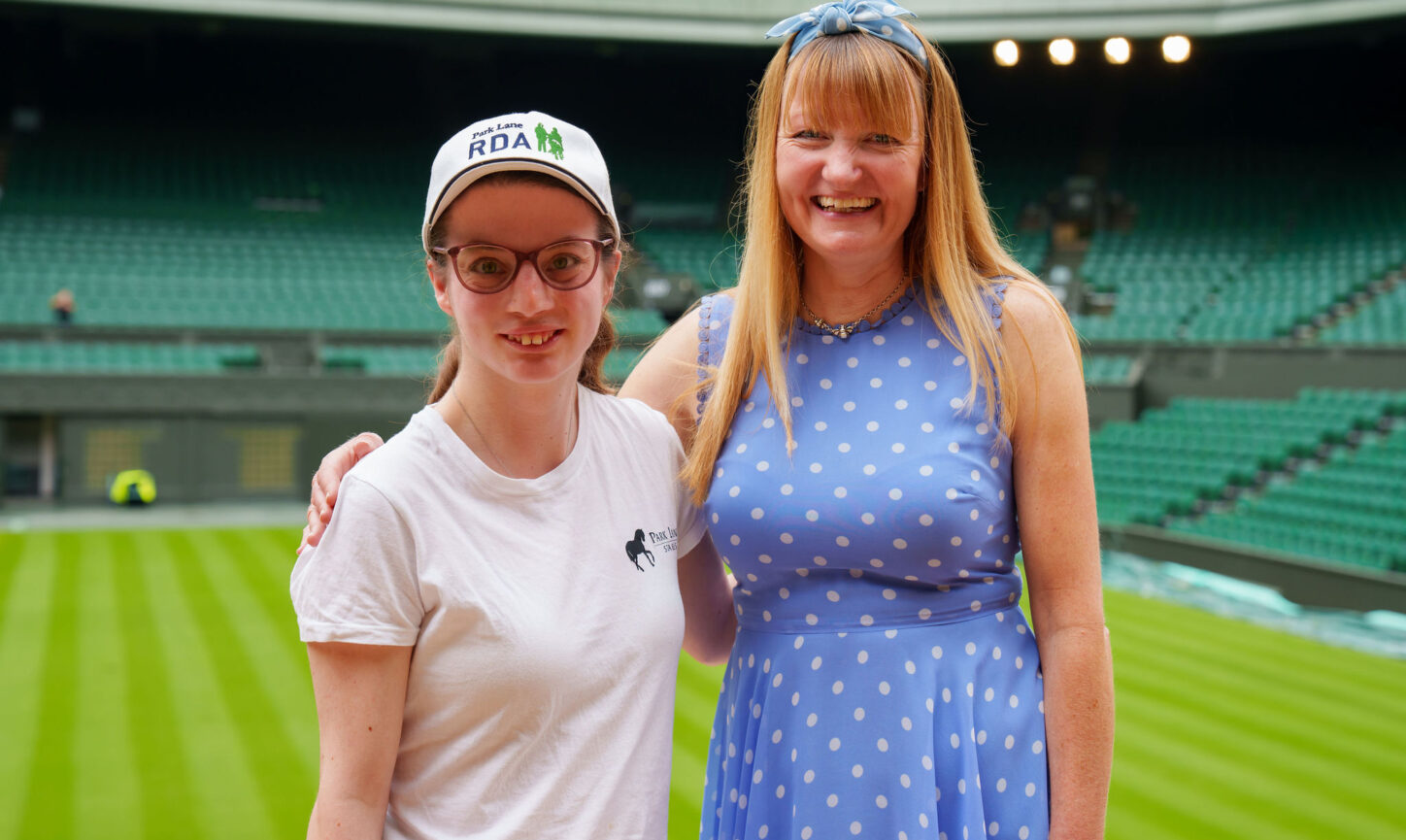 RDA participant Philippa George stands with Park Lane Stables RDA Group Chair Natalie O'Rourke against the backdrop of Wimbledon Centre Court.