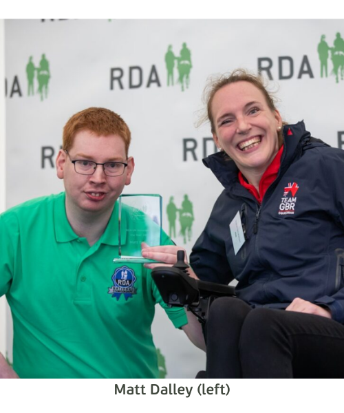 Two individuals proudly displaying a plaque at an RDA event, symbolizing their achievement and recognition.