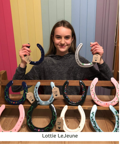 Lottie holds up her decorative horseshoes, she has painted.