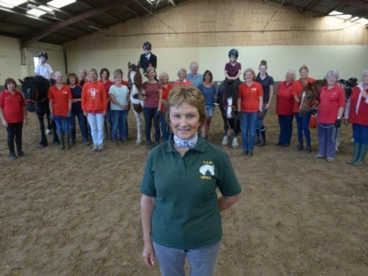 Carol Hipkin, the founder of Colchester RDA stands proudly in front of her team of ponies and volunteers.