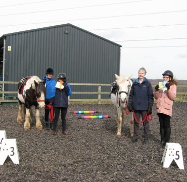 An awards session held to give riders their well earned rosettes. Anne is on the right-hand side holding the grey mare, Pride. Volunteer Patty holds pony Suzie.