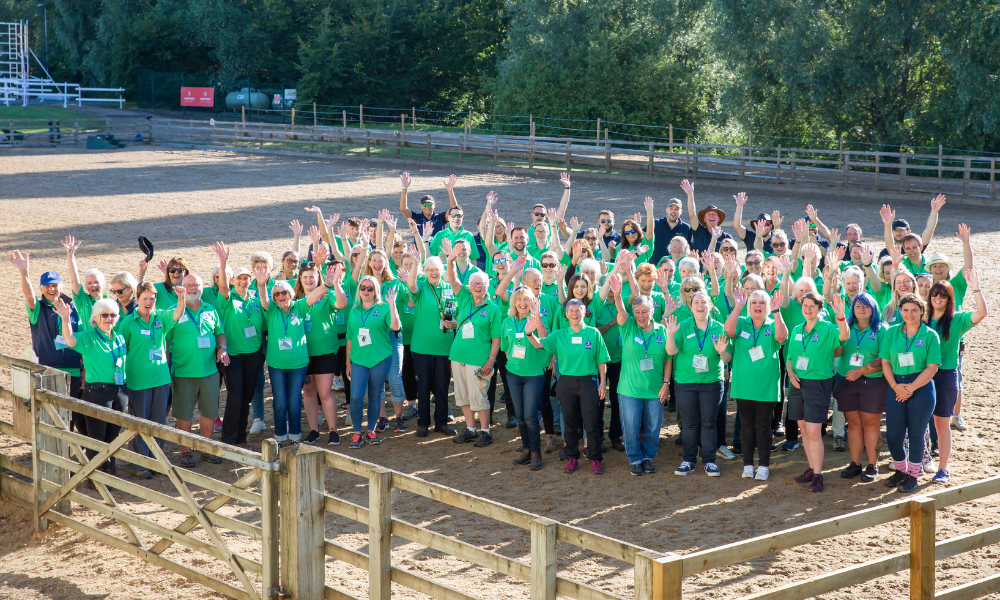 The Championships Volunteers cheer. Every volunteer is wearing a matching green polo shirt.