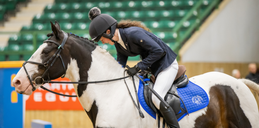 A rider pats her horse after finishing a clear round.