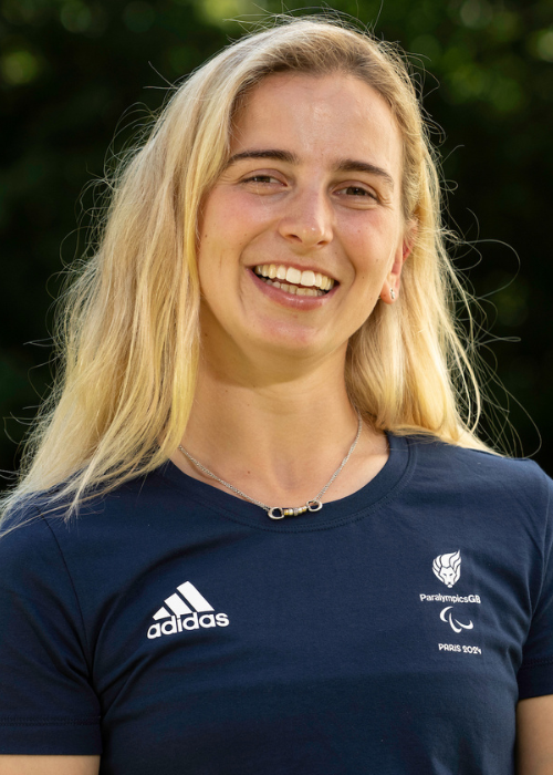 Georgia smiles, she has long blond hair. She wears a navy blue official paralympics team shirt.