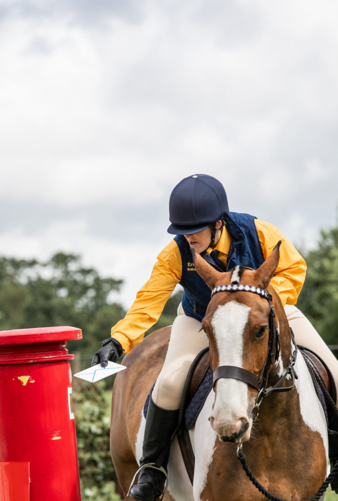 rider posting a letter into a red post box during countryside challenge