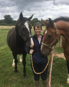 A woman with short hair holding two horses