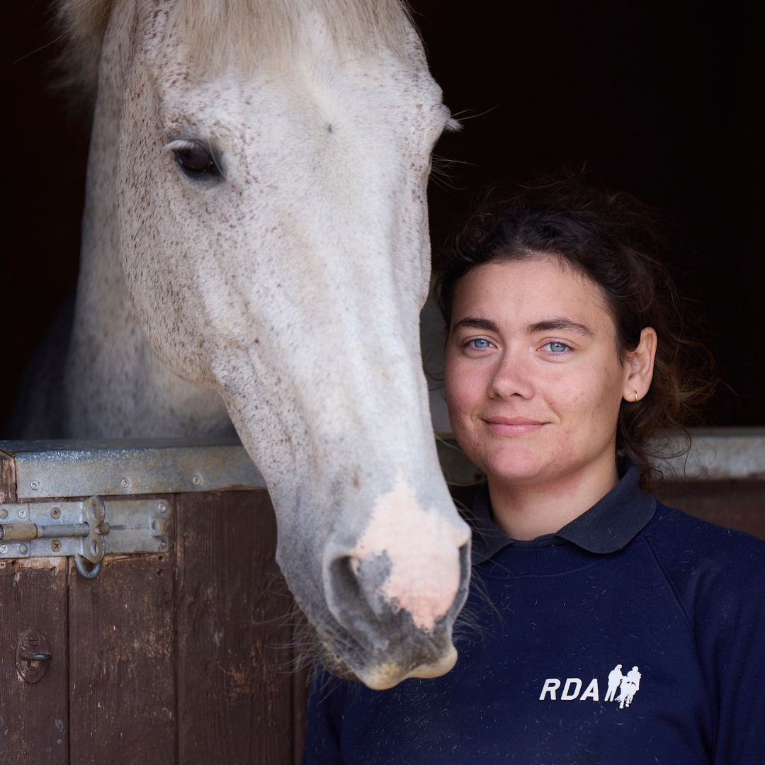 RDA volunteer stood next to a grey horse