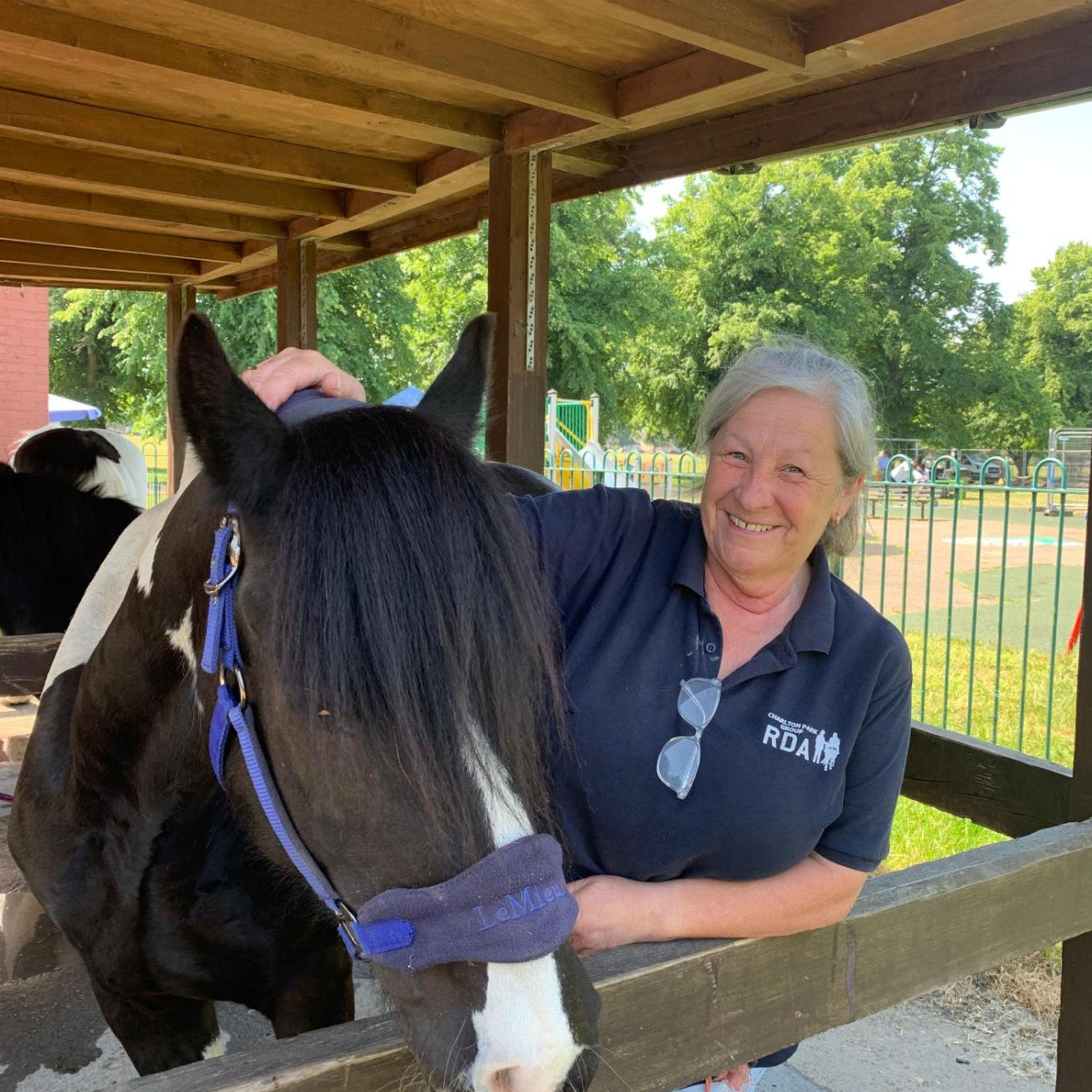 Carol Kendall stood next to a piebald horse, smiling at the camera.
