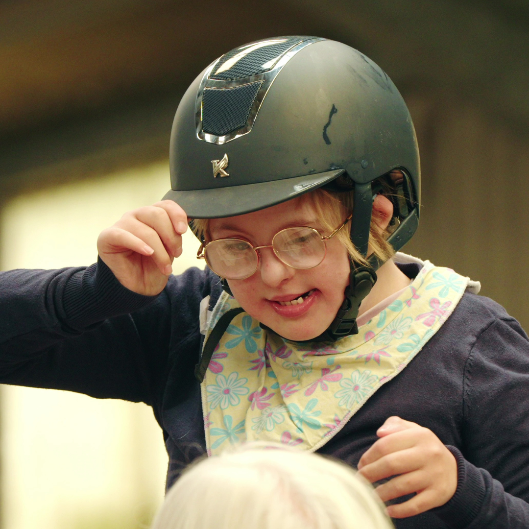 participant Hazel smiling and holding her riding hat